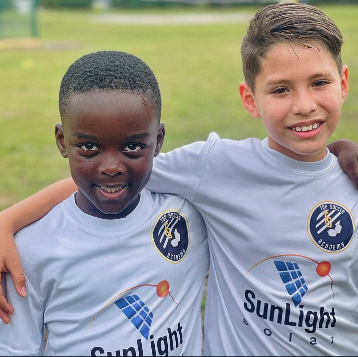 Two young Top Sports Academy athletes smiling together on the field