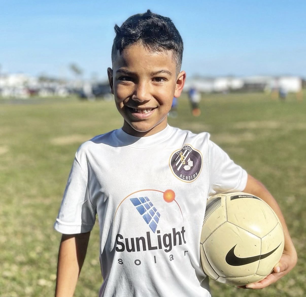 Young player smiling with a soccer ball at a Top Sports Academy training session